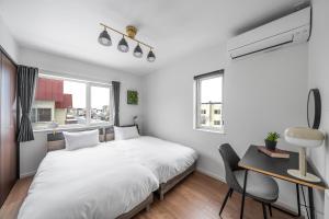 a white bedroom with a bed and a desk and window at Pregio Asahikawa in Asahikawa