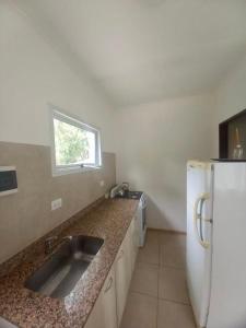 een keuken met een wastafel en een witte koelkast bij Viento Sur 2 in Estancia El Polomo +2 foto's