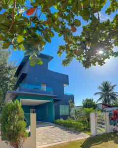 una casa azul con un árbol en Casa Bela Vista, en Japaratinga