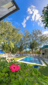 un patio trasero con piscina y flores en Casa Bela Vista, en Japaratinga