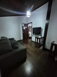 uma sala de estar com um sofá e uma televisão em Búzios Samba Suítes em Búzios
