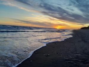een zonsondergang op een strand met de oceaan bij Viento Sur in Estancia El Polomo