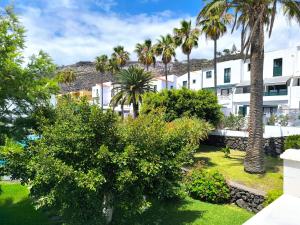 Blick auf ein Gebäude mit Palmen und Gras in der Unterkunft Amelia Cancajos - Confort Piscina y Playa cerca in Breña Baja