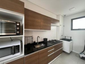 a kitchen with a microwave oven and a sink at Queridinho da praia de palmas in Governador Celso Ramos +5 photos
