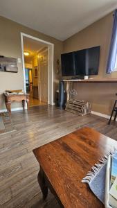 a living room with a table and a flat screen tv at Suite 1 Flèche du fjord vue Saguenay Monts Valin in Saint-Fulgence