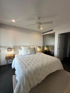 une chambre avec un lit blanc avec un ventilateur de plafond dans l'établissement Avalon Maroochydore, à Maroochydore