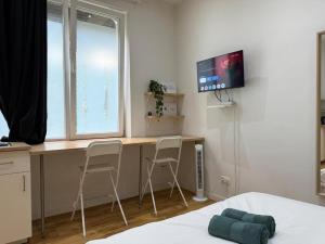 98 Apparthotel - Botanique 2 في لييج: غرفة نوم مع مكتب وكرسيين وتلفزيون