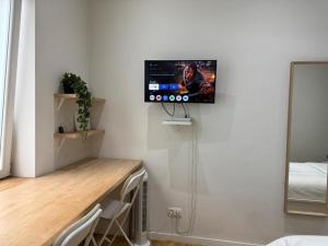 98 Apparthotel - Botanique 2 في لييج: غرفة بها مكتب وتلفزيون على الحائط +صورتان