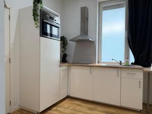 98 Apparthotel - Botanique 2 في لييج: مطبخ فيه دواليب بيضاء وثلاجة ونافذة