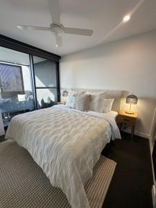 une chambre avec un grand lit blanc avec une fenêtre dans l'établissement Avalon Maroochydore, à Maroochydore
