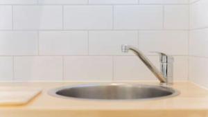 EpsomNouvelle Studio的厨房里设有不锈钢水槽,铺有白色瓷砖 更多1张照片