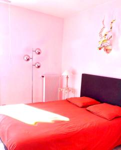 een slaapkamer met een rood bed met rode kussens bij Appartement spacieux à 10 minutes de la plage, vue mer in Menton