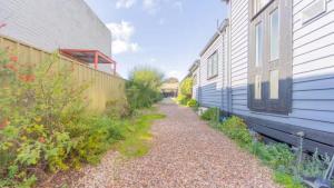 EpsomNouvelle Studio的建筑物旁边两栋建筑物之间的一条碎石小路