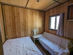 a bedroom with two beds and a chair in it at Tiny Wood Cottage 08 in Wasaga Beach