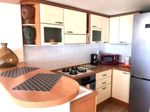 een keuken met witte kasten en een houten aanrechtblad bij Appartement spacieux à 10 minutes de la plage, vue mer in Menton