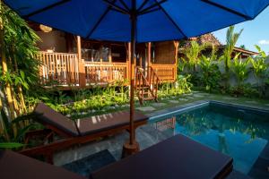 a house with an umbrella and a swimming pool at Langkih Private Villas in Tegalalang