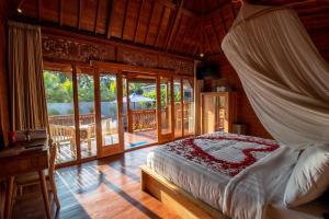 a bedroom with a canopy bed and a balcony at Langkih Private Villas in Tegalalang