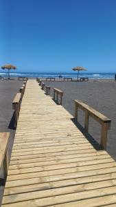 a wooden boardwalk on the beach with umbrellas at Cabaña Campestre in El Cerrillo
