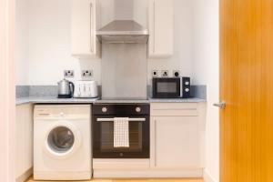 a kitchen with a microwave and a washer and dryer at The Central Suite in Manchester
