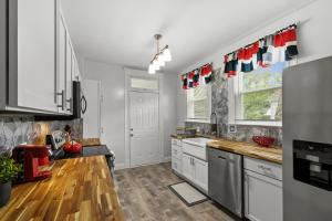 a kitchen with white cabinets and a wooden floor at Spacious Cottage near Airport, Hospitals, and Highways in Bel-Ridge +11 photos