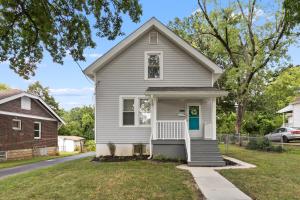 a gray house with a blue door on a street at Spacious Cottage near Airport, Hospitals, and Highways in Bel-Ridge