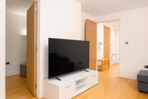 a living room with a flat screen tv on a white cabinet at The Central Suite in Manchester