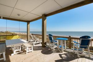 a deck with a table and chairs and the beach at Deja Blue home in Caplen