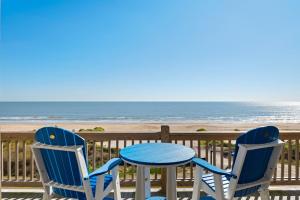 two chairs and a table on a deck with the beach at Deja Blue home in Caplen
