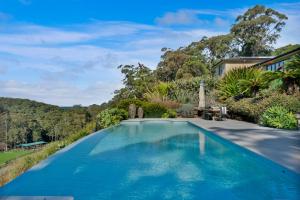 a swimming pool in front of a house with trees at The Outlook Cabana in Terrigal