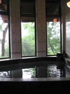a swimming pool in a building with windows at Pension Noel in Kaminoyama