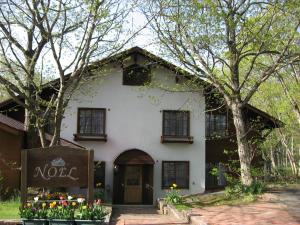 a white house with flowers in front of it at Pension Noel in Kaminoyama