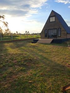 a house on a field with a grass yard at Cabaña Alpina Zen in Carmen del Paraná