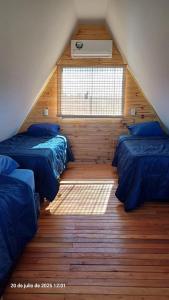 a attic bedroom with two beds and a window at Cabaña Alpina Zen in Carmen del Paraná