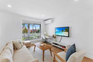 Erowal BayにあるThe Pearl A Fresh, Modern Family Retreat in Old Erowal Bayのソファとテレビのあるリビングルーム