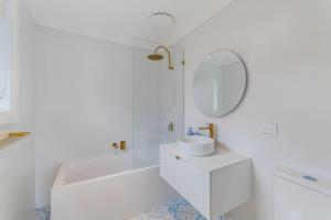 Erowal BayにあるThe Pearl A Fresh, Modern Family Retreat in Old Erowal Bayの洗面台と鏡のある白いバスルーム +7枚の写真