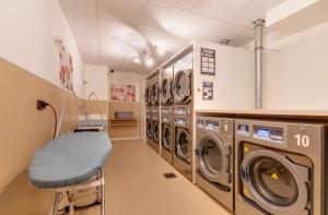 a laundry room with washing machines and a blue chair at River Residenz Basel&Huningue in Huningue