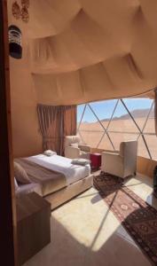 a bedroom with a bed and chairs and a large window at Wadirum Leen camp in Wadi Rum