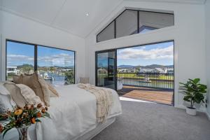 a bedroom with a bed and a large window at Luxury Beach Retreat - Mountain Views & Boat Jetty in Whitianga