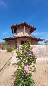 a stone building with flowers in front of it at Chalé Gravatinha in Mucugê