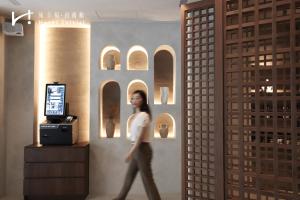 Una mujer caminando en una habitación con una pared con arcos. en Hotel Initial-Tainan, en Tainan