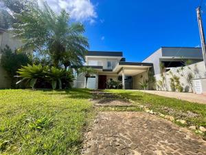 a house with a palm tree next to a driveway at Mansão Maretti in Bertioga