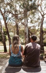 a man and woman sitting on a bench in a park at Romantic Lakefront Luxury - Spa Bath, Fireplace, King Bed in Daylesford