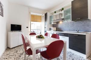 アルゲーロにあるSeaside Holidaysのキッチン(白いテーブル、赤い椅子付)
