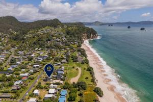 an aerial view of a beach with houses and the ocean at Hosts on the Coast Hahei Sands Villa A in Hahei