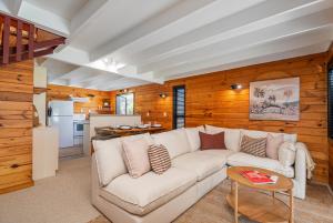 a living room with a white couch and a kitchen at Hosts on the Coast Hahei Sands Villa A in Hahei +21 photos