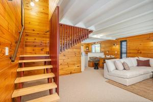 a living room with a white couch and wooden walls at Hosts on the Coast Hahei Sands Villa A in Hahei