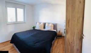 1 dormitorio con 1 cama con sábanas negras y almohadas blancas en Neue Ferienwohnung Bad Dürrheim Kurgebiet, Neue 3 Zimmer Wohnung Kurgebiet, en Bad Dürrheim