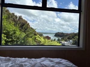 a bedroom window with a view of the water at Tuis Nest, family beach bach at Opito Bay in Kerikeri +11 photos