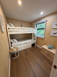 two bunk beds in a room with a window at Tuis Nest, family beach bach at Opito Bay in Kerikeri