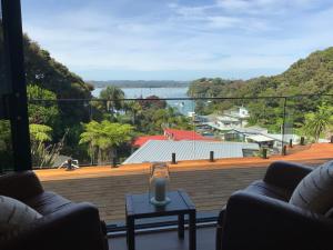 a living room with a large balcony with a view of the water at Tuis Nest, family beach bach at Opito Bay in Kerikeri